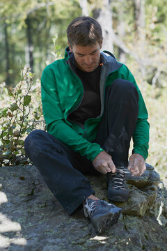 Climber tying shoelace, Chamonix, Rhone-Alps, France