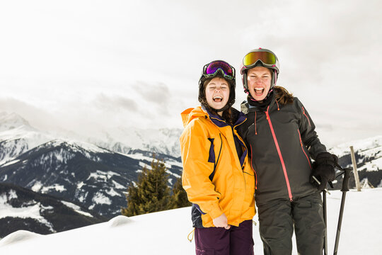 Two skiing women laughing on snow covered mountain, Gerlos, Tyrol, Austria