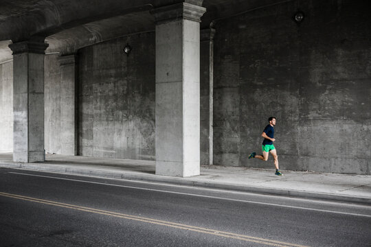 Young male runner running through underpass