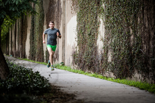 Young male runner running along urban path