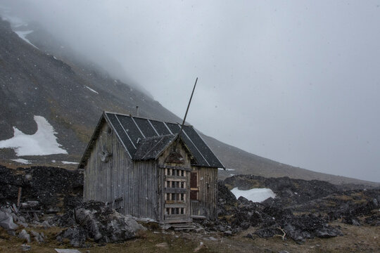 Abandoned cabin in mountain landscape. Varsolbukta, Bellsund bay, Van Mijenfjorden, Spitsbergen, Svalbard, Norway