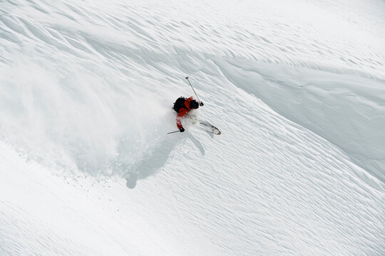 Male skier skiing down mountainside, high angle view, Alpe-d'Huez, Rhone-Alpes, France