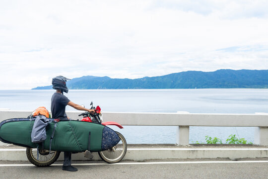 Motorcyclist carrying surfboard on bike, Pagudpud, Ilocos Norte, Philippines