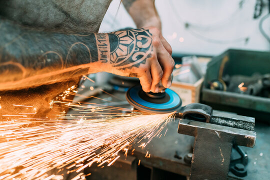 Axe maker using steel grinder in workshop