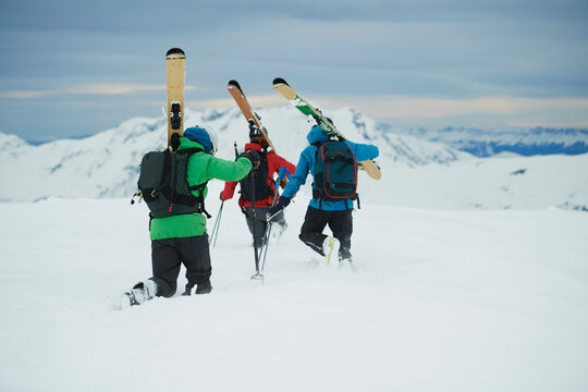 Landscape with three male skiers trudging toward mountain, rear view, Alpe-d'Huez, Rhone-Alpes, France