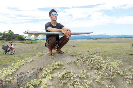 Surfer with surfboard on beach, Abulug, Cagayan, Philippines