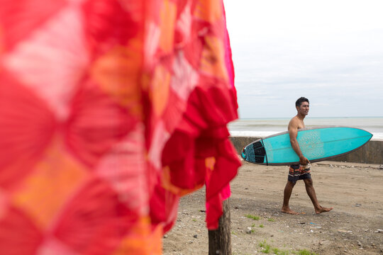 Surfer with surfboard on beach, Abulug, Cagayan, Philippines