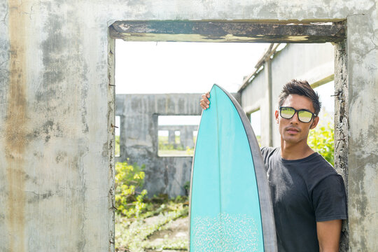 Surfer by doorway of abandoned building, Abulug, Cagayan, Philippines