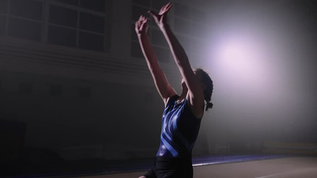 sporty female adolescent is performing two flips on floor, rotating back, training, preparing to competition