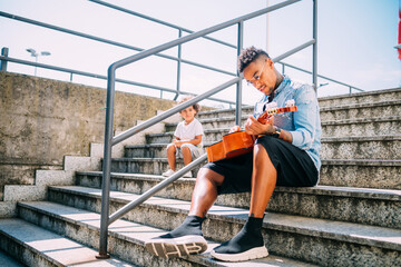 Toddler watching father play guitar on stairway