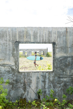 Surfer seen through window of abandoned building, Abulug, Cagayan, Philippines