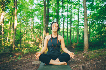 Woman doing enlightened pose in forest