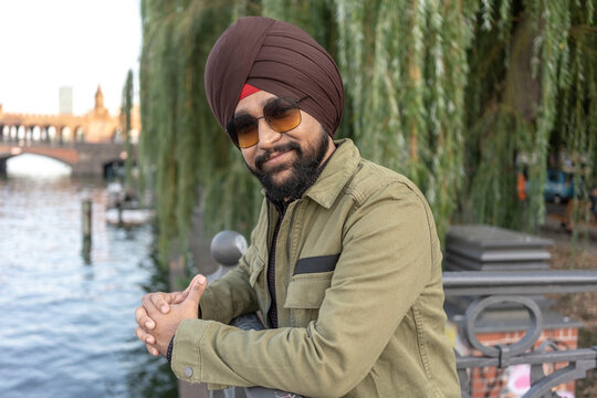 Indian man exploring city, river in background, Berlin, Germany
