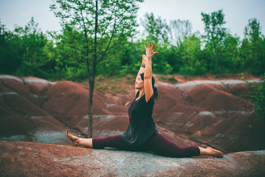 Woman doing monkey pose on rock