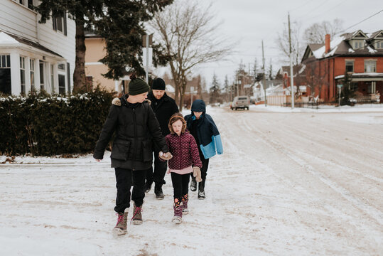 Parents and children walking on snow covered street