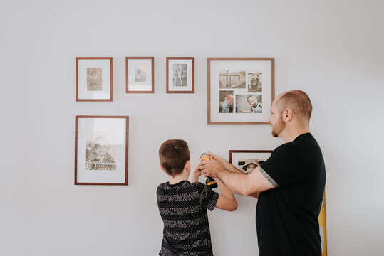Father teaching son drill wall for picture frames