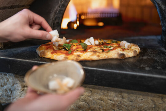Chef placing prawns onto Pinsa Romana base, a Roman style pizza blend reducing sugar and saturated fat, containing rice and soy with less gluten, close up of hands
