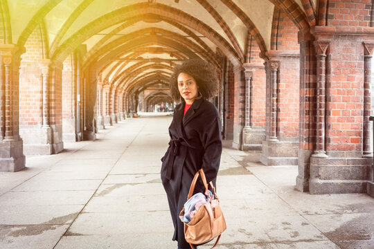 Mid adult woman in stylish coat under archway of Oberbaum Bridge, portrait, Berlin, Germany