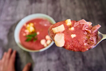 Spoon full of gazpacho cold soup with accompaniment ready to taste in focused close-up view, with...