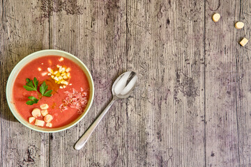 Zenith view of a gazpacho bowl with complements and a spoon at the right. Concept of mediterranean food, healthy.