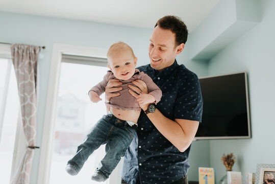 Father playing with baby son in living room