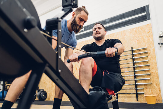 Personal trainer working with man with disability on rowing machine
