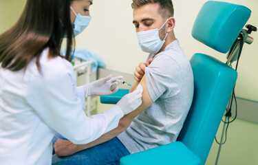 Covid-19 or coronavirus vaccine doctor holding syringe and using cotton before making injection to the patient in the medical mask.