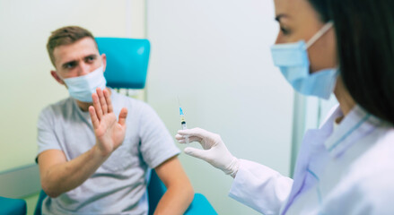 No Vaccination. Scared Man Gesturing Stop To Hand Offering Syringe With Vaccine Refusing To Be Vaccinated. Needle Phobia, Fear Of Covid-19 Vaccines