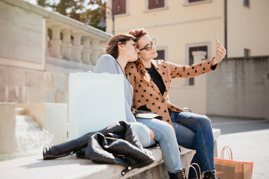 Female shoppers taking selfie in front of fountain, Arezzo, Toscana, Italy
