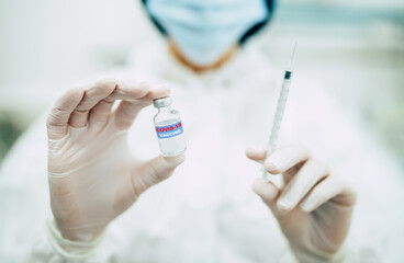 Doctor, nurse, or a scientist in blue gloves holding covid-19 vaccine disease preparing for human clinical trials vaccination shot, medicine, and drug concept.