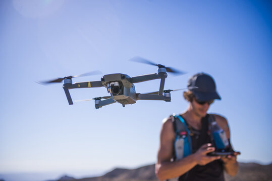 Man operating drone (unmanned aerial vehicle) against blue sky, Nelson, Nevada, USA