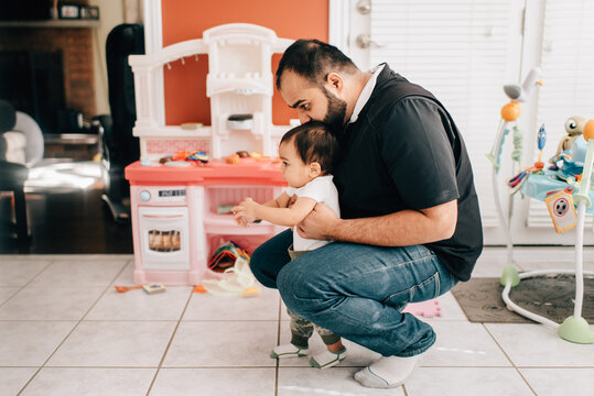 Father crouching in kitchen with baby son