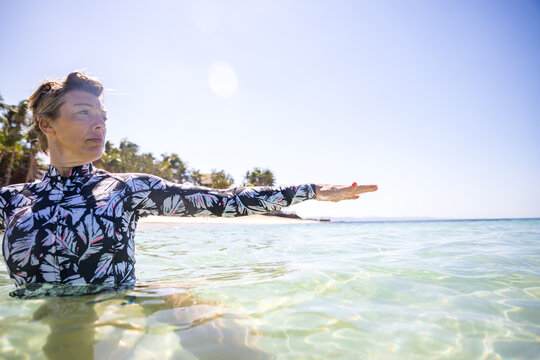 Woman stretching hand in sea, Pagudpud, Ilocos Norte, Philippines