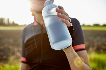 Female cyclist drinking from water bottle, cropped