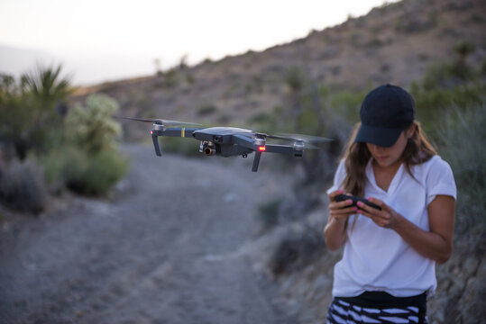 Woman operating drone (unmanned aerial vehicle) on rural dirt track
