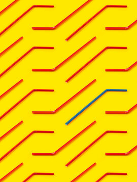 Red and blue straws laid diagonally on yellow background