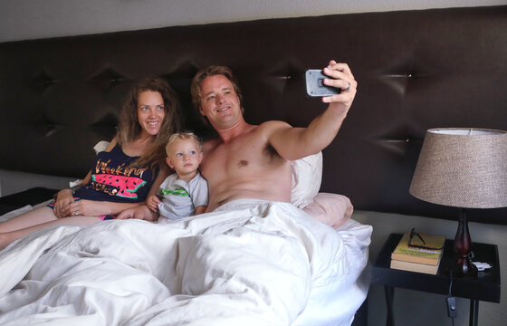 Couple with baby son taking selfie in bed