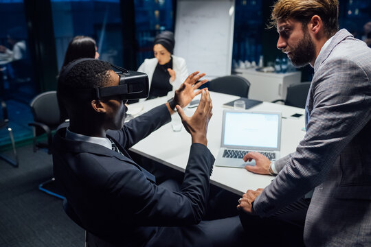 Businessman looking through virtual reality headset during conference table meeting