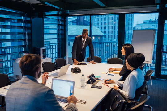Businessman talking to team during conference table meeting