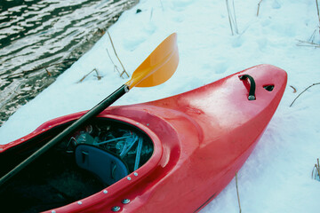 Kayak and paddle on riverbank in winter, cropped