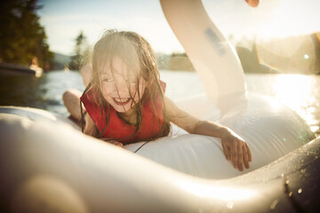 Girl playing on inflatable swan in lake