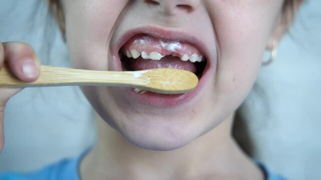 Morning brushing teeth hygiene. A child making her morning brushing hygiene with a paste and bamboo brush in the room.
