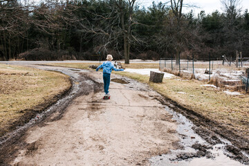 Boy skateboarding along dirt track, rear view