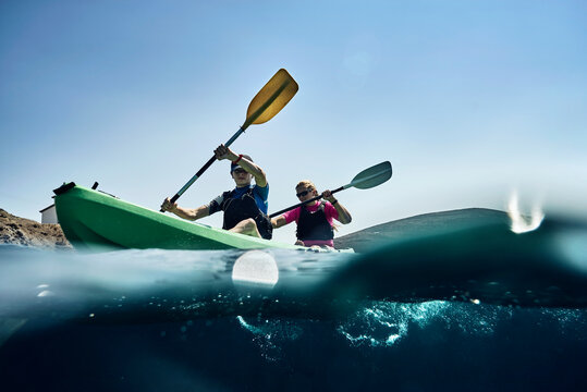 Teenage boy and mother sea kayaking on ocean, surface level view, Limnos, Khios, Greece