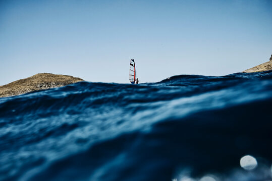 Young man windsurfing ocean waves, distant surface level view, Limnos, Khios, Greece