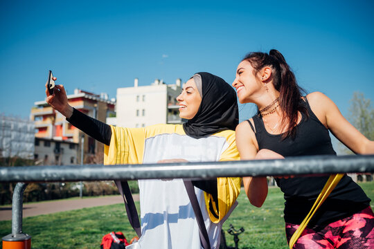 Calisthenics class at outdoor gym, two young women taking smartphone selfie