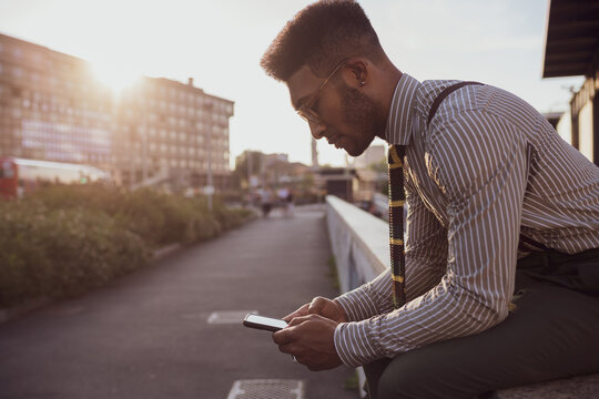 Businessman using smartphone by pavement, Milano, Lombardia, Italy