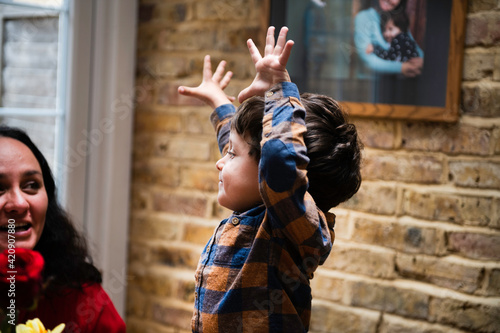 Male toddler with hands raised looking at mother, celebrating mothers day