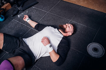 Exhausted young man taking break in gym