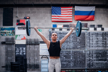 Young woman lifting barbell in gym